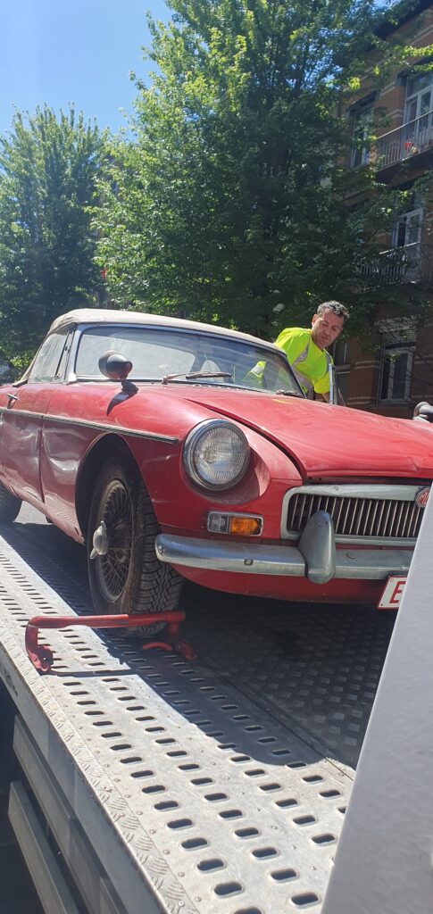 Dépanneur en train d’attacher une ancienne voiture sur une dépanneuse